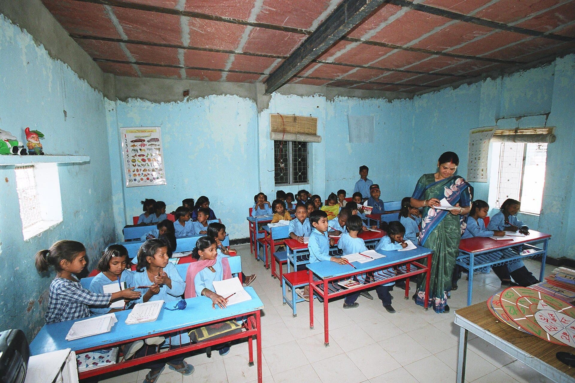 A teacher with children at their desks in a primary school classroom